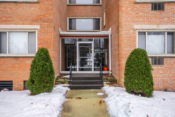 Entrance of a brick building with glass doors and steps leading to it.