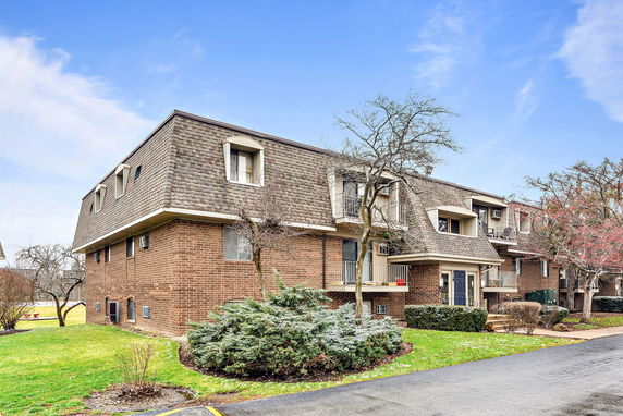 Front view of a multi-story apartment building with brick exterior and multiple windows.