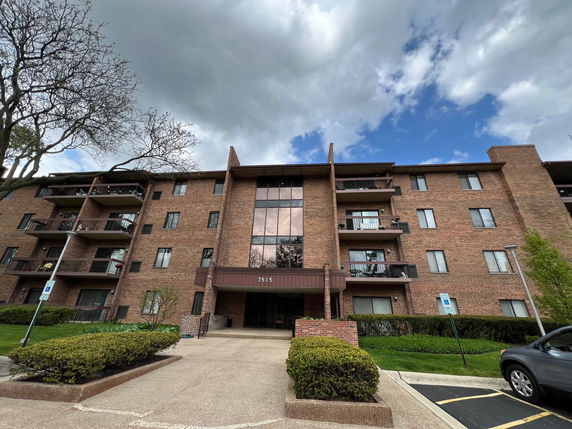 Front view of a multi-story brick apartment building with balconies.