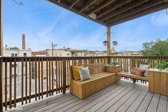 View from a wooden balcony overlooking neighboring rooftops and a clear sky.