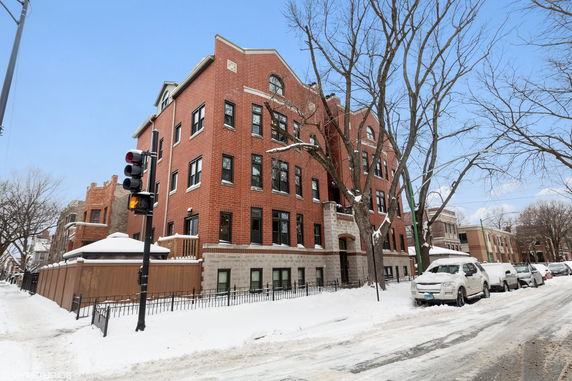 Front view of a multi-story brick apartment building in a snowy setting.