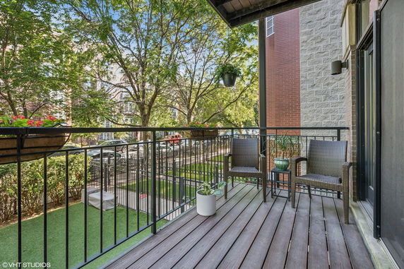 View from a balcony showing surrounding residential area with trees and buildings.