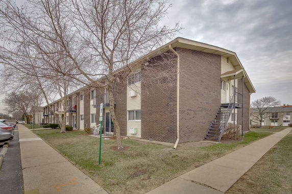 Front view of a brick apartment building with an external staircase.