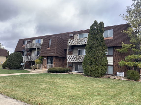 Front view of a multi-story brick apartment building with balconies.