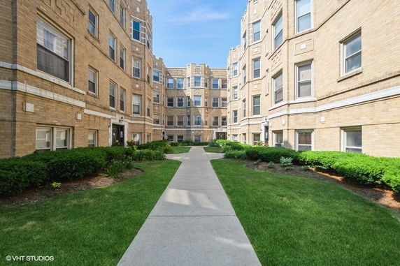 Front view of a multi-story brick apartment building with a central pathway.