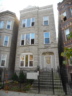Front view of a three-story residential building with a gated entrance.