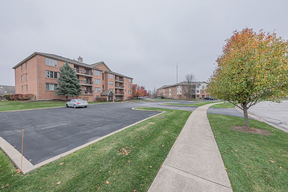 Front view of a multi-story apartment building with a parking area.