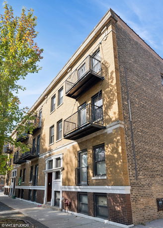 Front view of a multi-story brick apartment building with balconies.