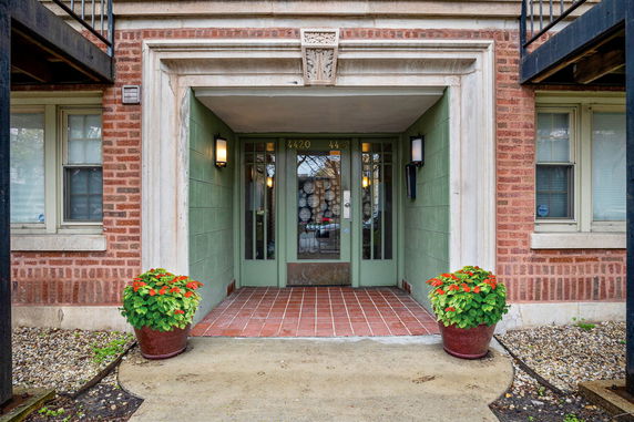 Front entrance of a brick building with green doors and decorative elements.