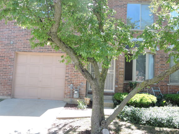 Front view of a brick house with a garage and large windows.
