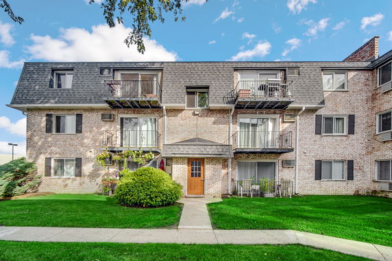 Front view of a three-story apartment building with balconies and a shingled roof.