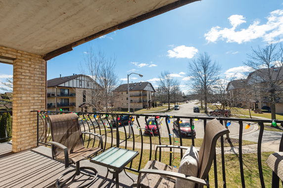 View from a balcony overlooking a residential street with apartment buildings.