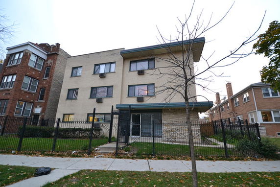 Front view of a three-story apartment building with a fenced yard.