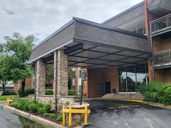 Front view of a building with a covered entrance supported by stone pillars.