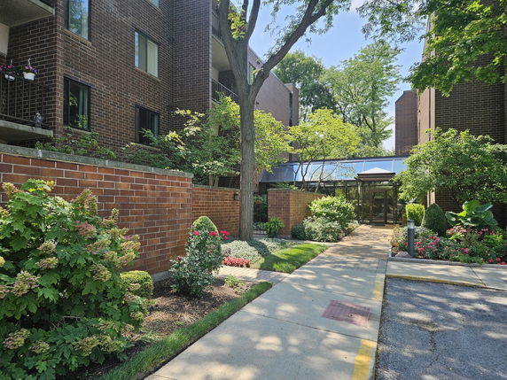 Front view of a multi-story brick building with landscaped entrance.