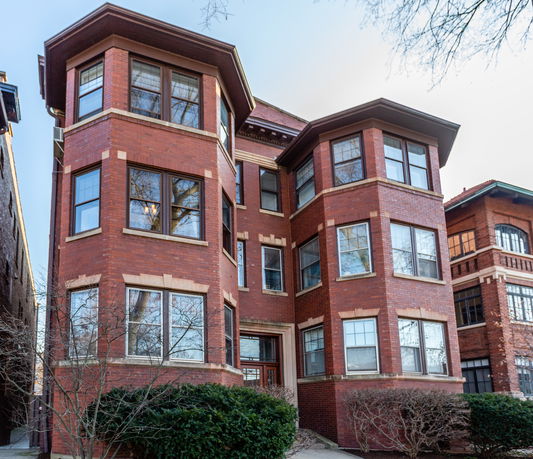 Front view of a multi-story brick building with large bay windows.