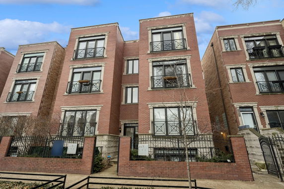 Front view of a multi-story brick residential building with balconies.