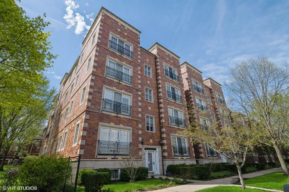 Front view of a multi-story brick apartment building with decorative balconies.