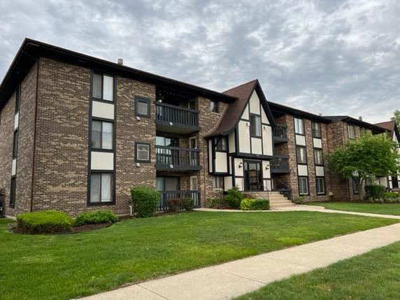 Front view of a three-story apartment building with brick exterior and balconies.