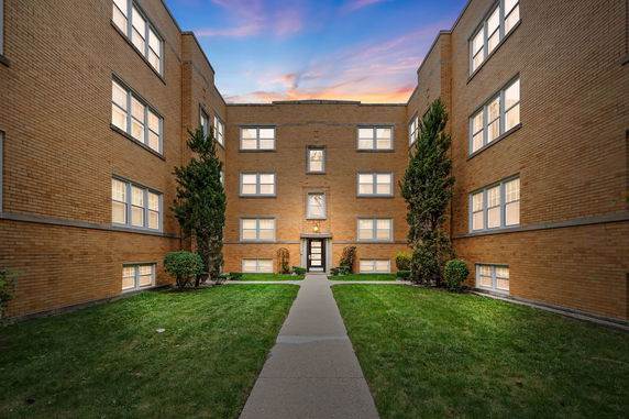 Front view of a multi-story brick building with a pathway and entrance.