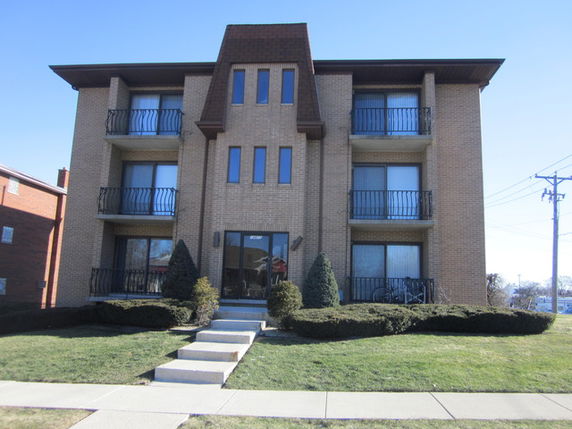 Front view of a three-story apartment building with balconies.