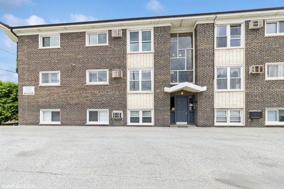 Front view of a three-story brick building with multiple windows.