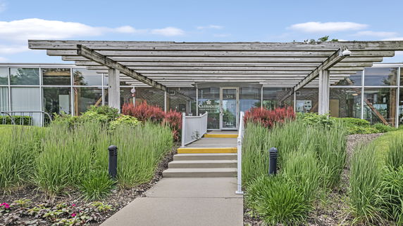 Front view of a building with a wooden pergola entrance and glass windows.