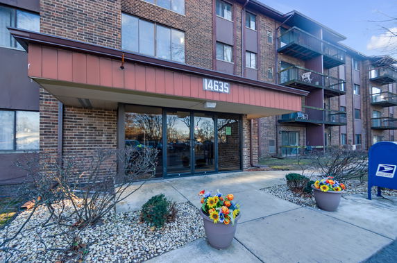 Front view of a multi-story brick apartment building with balconies.
