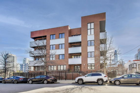 Front view of a multi-story brick apartment building with balconies.