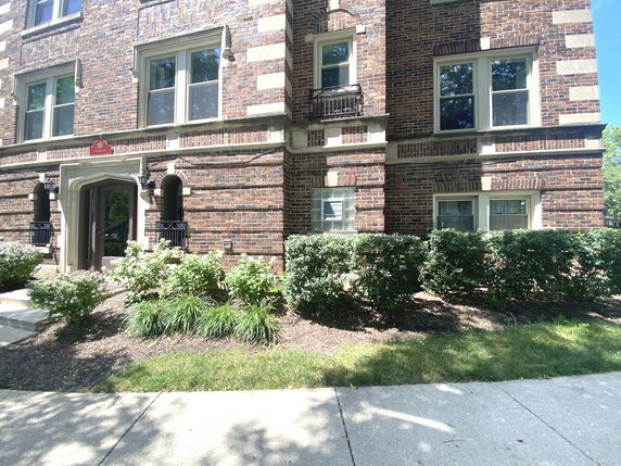 Front view of a multi-story brick house with decorative trim and multiple windows.
