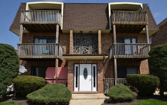 Front view of a multi-story brick building with balconies and a central entrance.