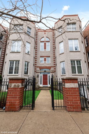 Front view of a multi-story brick building with a central entrance and bay windows.