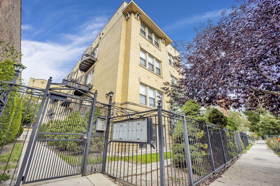 Front view of a four-story brick apartment building with entrance gate.