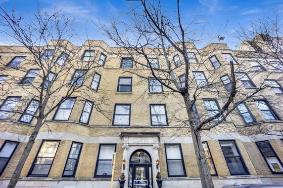 Front view of a multi-story building with large windows and decorative entrance.