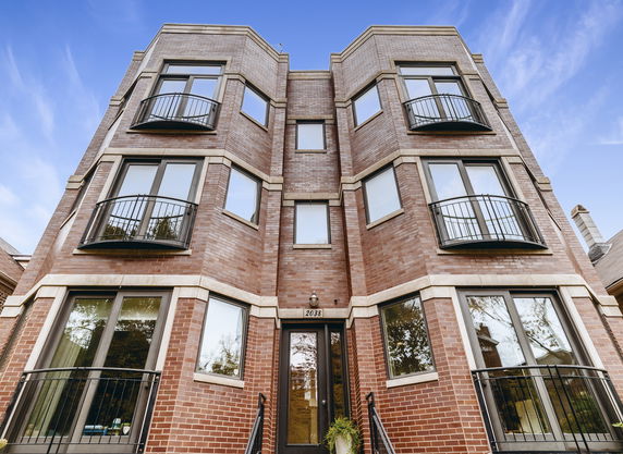 Front view of a multi-story brick apartment building with balconies.