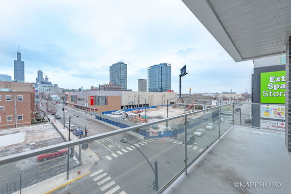 View from a balcony overlooking a city street and distant skyscrapers.
