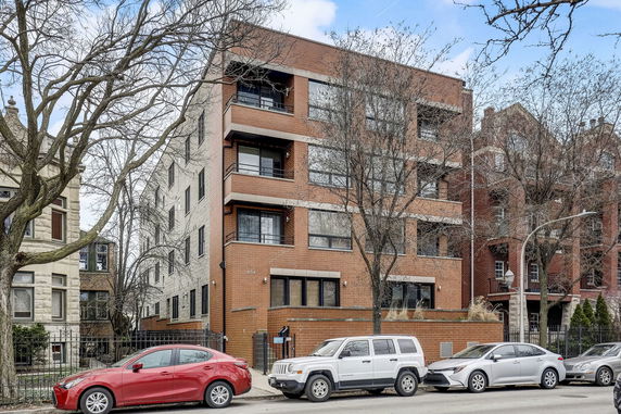 Front view of a multi-story brick apartment building with balconies.