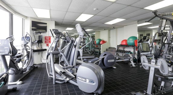 Indoor gym area with various fitness equipment including treadmills, ellipticals, and weights.