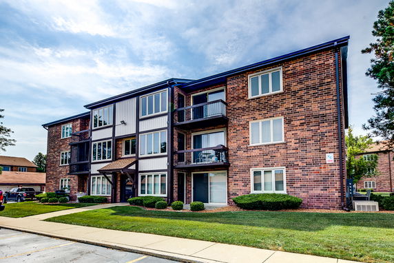 Front view of a three-story brick apartment building with multiple windows and balconies.