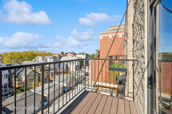 Elevated view from a building balcony showing nearby rooftops and cityscape.