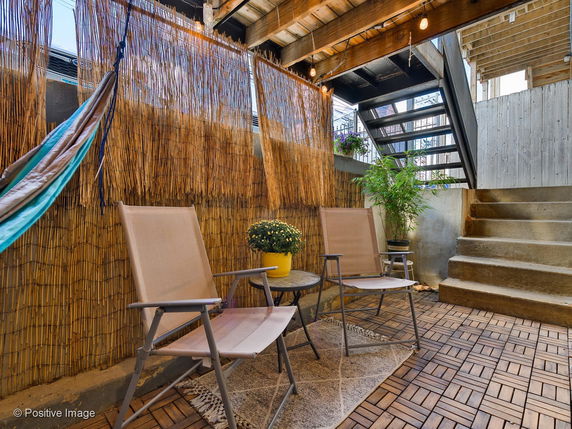 Outdoor area with chairs, hammock, and stairs leading upward.