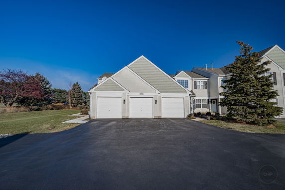 Front view of a house with triple garages and dormer windows.