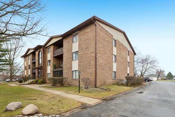Front view of a multi-story apartment building with brick and siding exterior.
