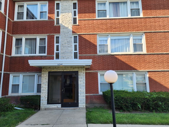 Front view of a multi-story brick apartment building with large windows.