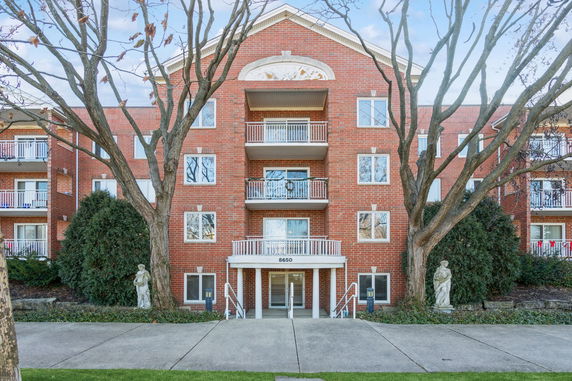 Front view of a multi-story brick apartment building with balconies.