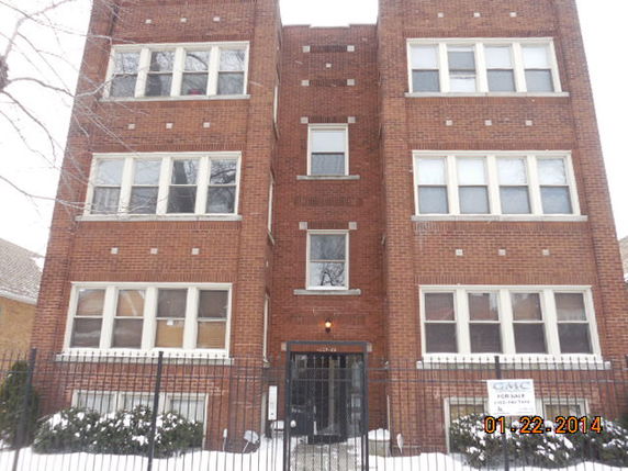 Front view of a brick apartment building with multiple stories and large windows.
