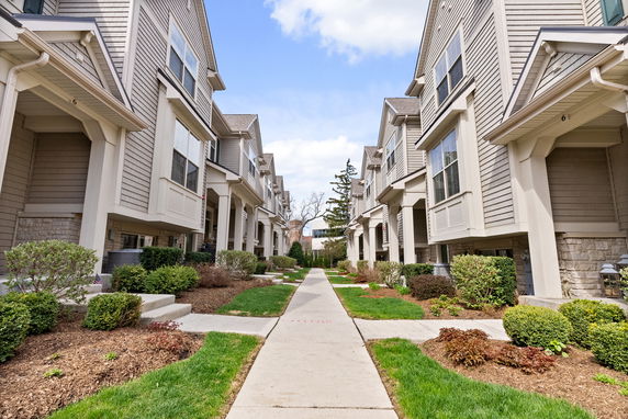 Front view of multiple townhouse buildings with entrance pathways and landscaping.