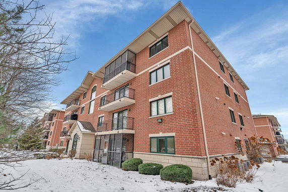 Front view of a multi-story brick building with balconies and large windows.