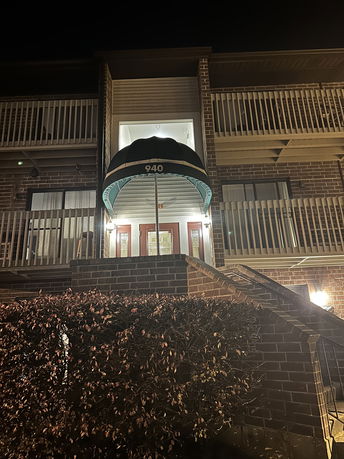Front view of a multi-story building with balconies and an entrance awning.