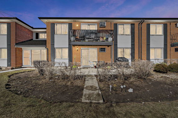 Front view of a two-story brick house with a balcony and patio.